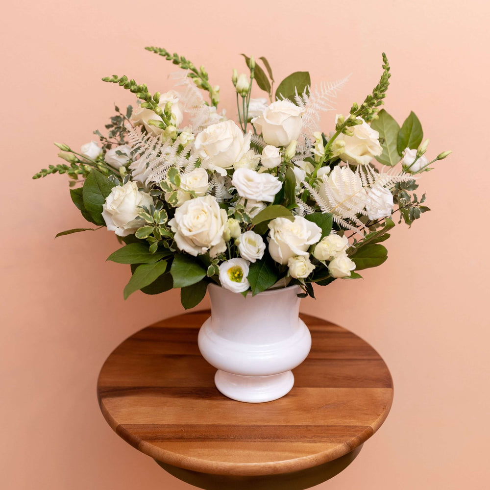White sympathy floral arrangement with white vase